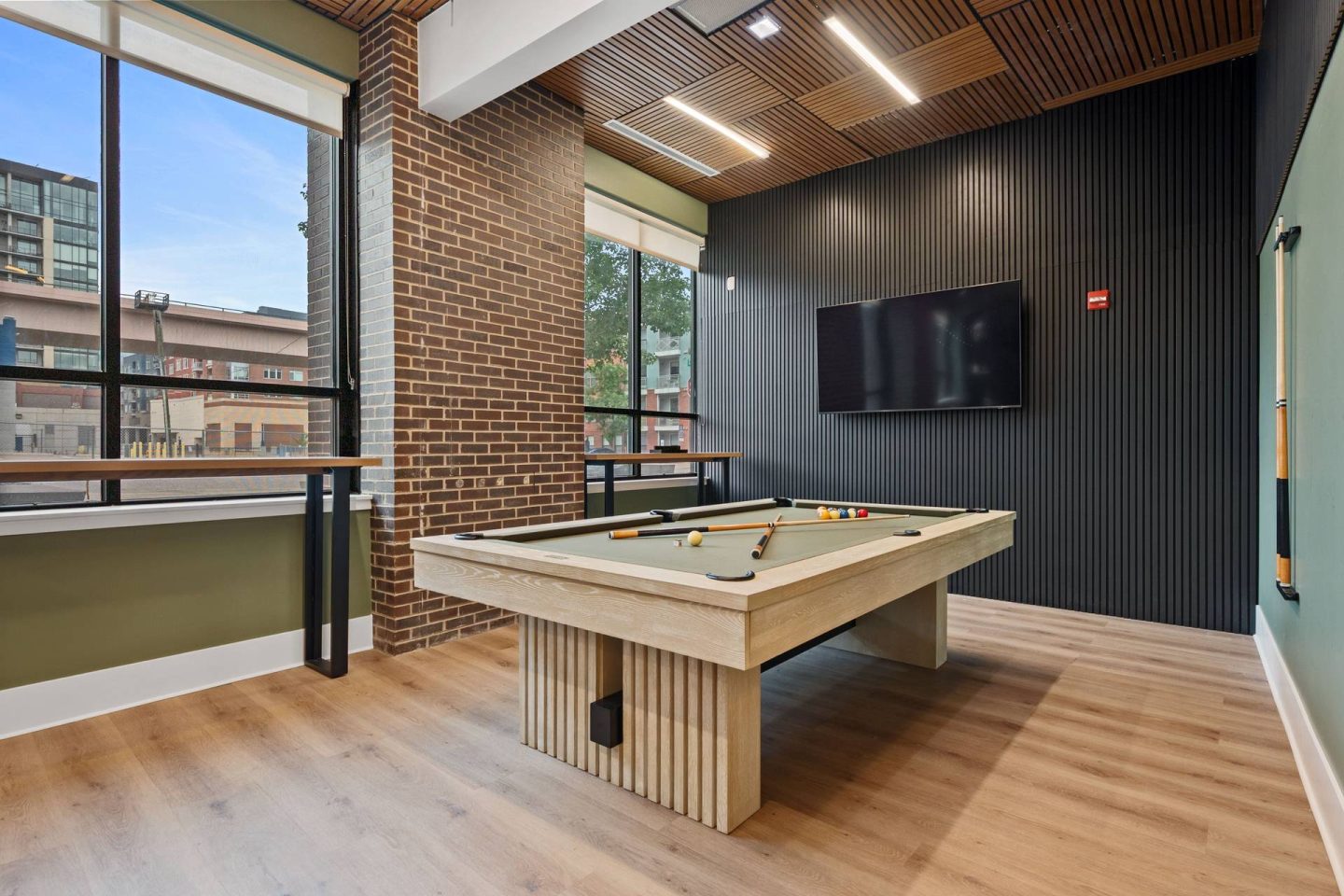 A pool table in a room with a brick wall and a television at The Casey, Colorado 80202