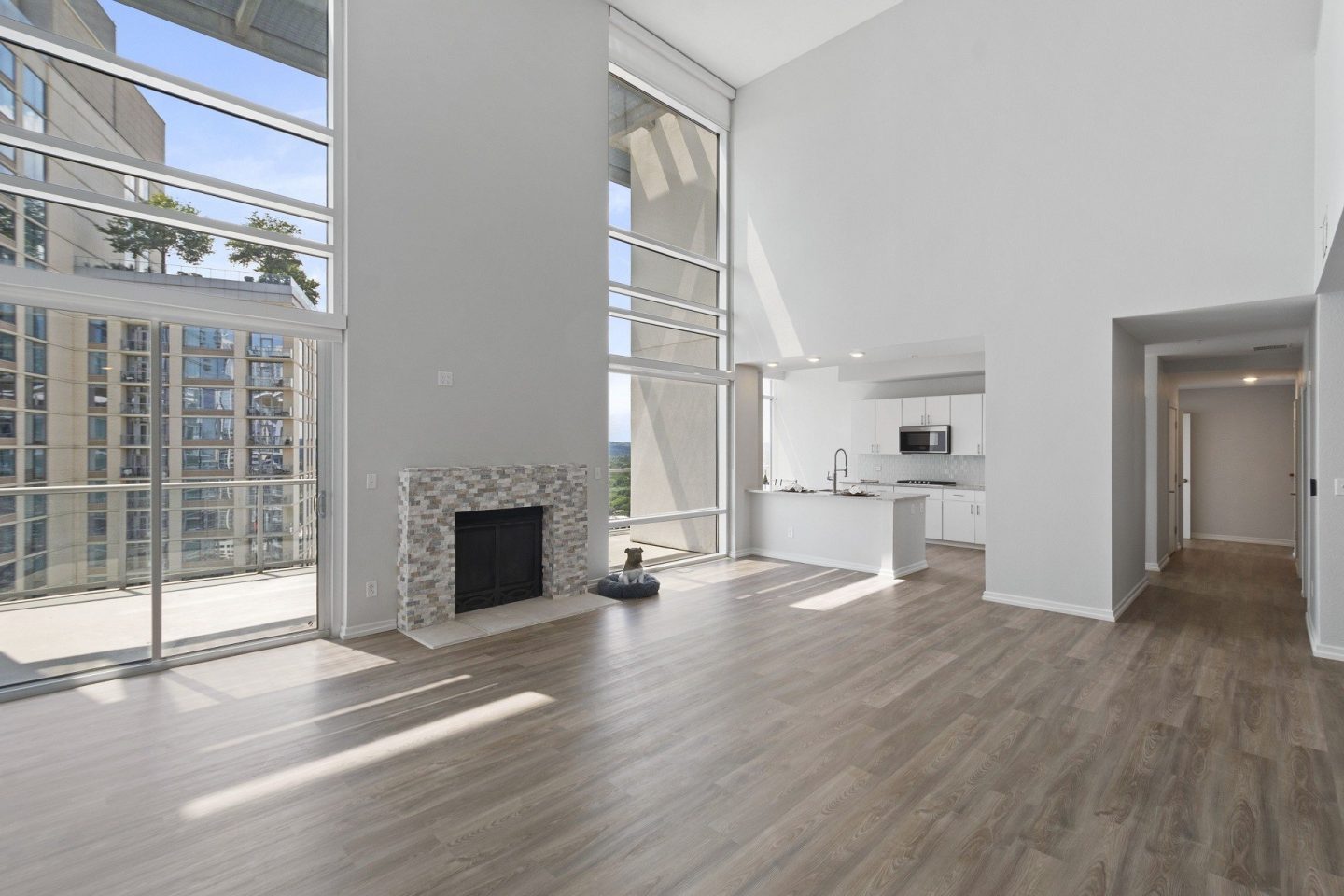 A modern living room with a fireplace and a view of a cityscape through the windows.