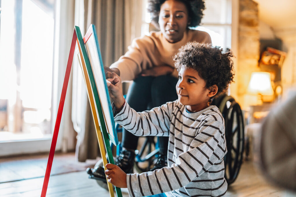 woman sitting in wheelchair and young boy looking at easel