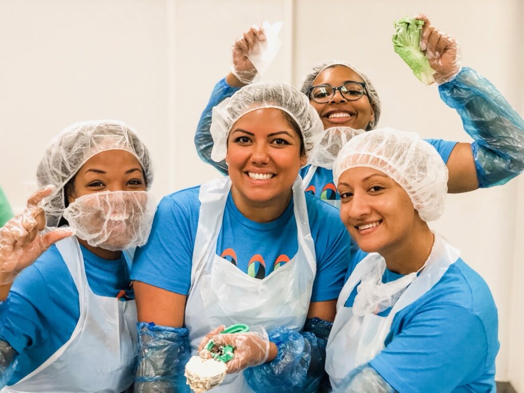 four smiling women volunteering at local food bank
