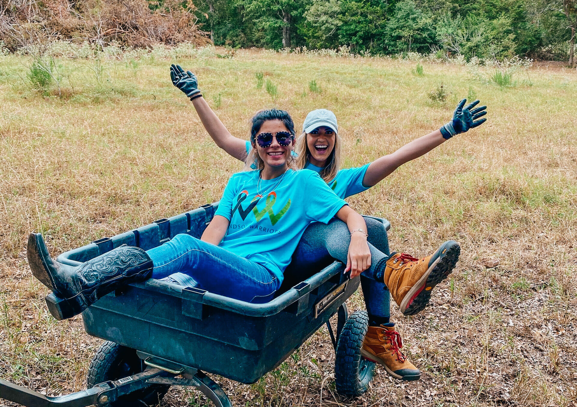 Two Windsor associates sitting in a wheelbarrow on a volunteer day