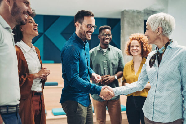 Professionals in an office shaking hands, representing networking opportunities and career growth in a hub for industry leaders.