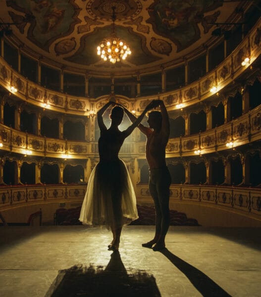 Cinematic shot of Young Couple of Classical Ballet Dancers Performing on the Stage of Classic Theatre with Dramatic Lighting. Male and Female Dancers Rehearse their Performance Together Before a show