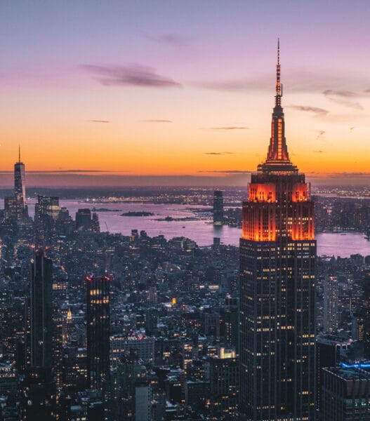 Bird's eye view of skyscrapers and Empire State Building illuminated at sunset in New York, USA