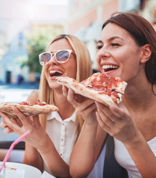 Pizza time. Young girls eating pizza in a cafe. Consumerism, lifestyle