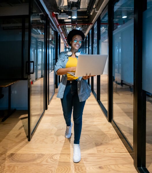 Happy IT technician working at the office using her laptop