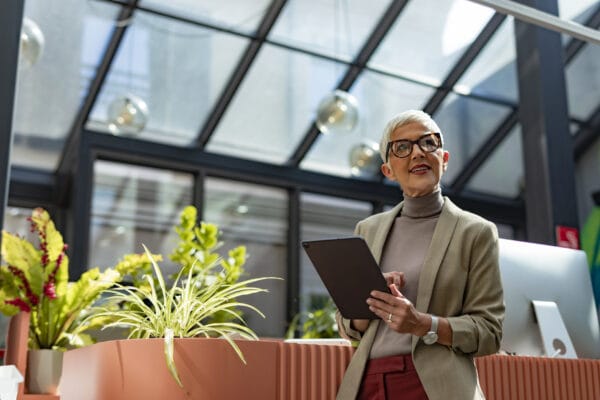 Confident, Happy Senior Businesswoman with Short Hair Standing outside and Holding a Digital Tablet