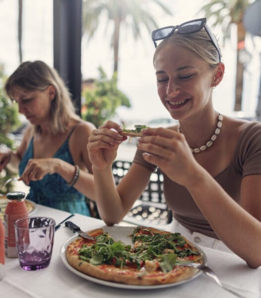 Mother and teenage daughter enjoying pizza lunch in a restaurant in an Italian town