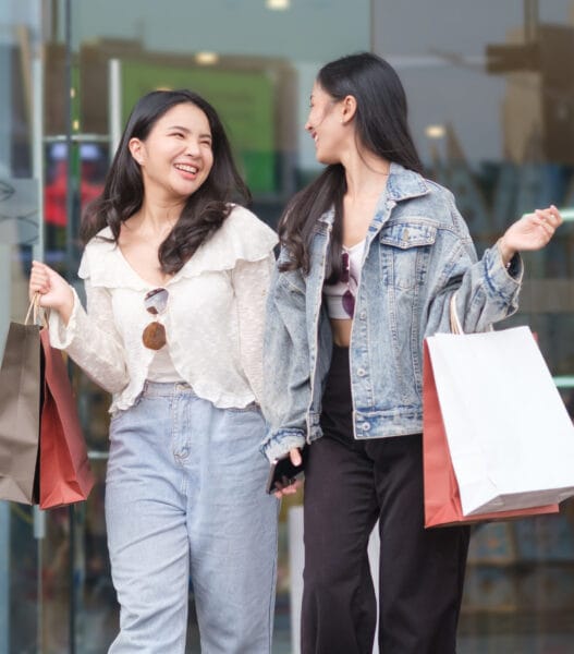 Joyful young woman carrying shopping bags walking out from shop and laughing, enjoying sales weekend.